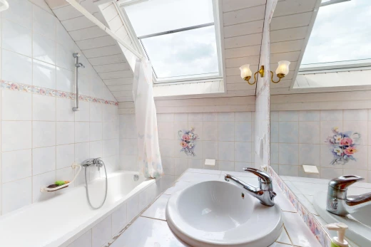 salle de bain avec mur carrelé, lumière naturelle, plafond voûté, vasque, et bain-douche