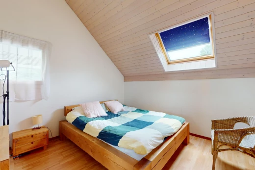 chambre avec plancher de bois, plafond voûté, lucarne, et lumière naturelle