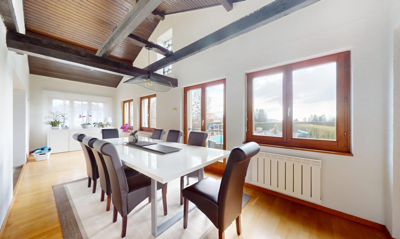 salle à manger avec lumière naturelle, plafond voûté, radiateur, sol en finition bois, et plafond à poutres