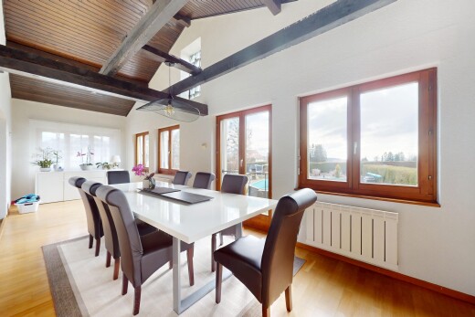 salle à manger avec lumière naturelle, plafond voûté, radiateur, sol en finition bois, et plafond à poutres