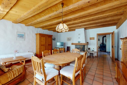 esszimmer mit fernseher, bemerkenswerter kronleuchter, holzofen, fliesenboden, und balkendecke