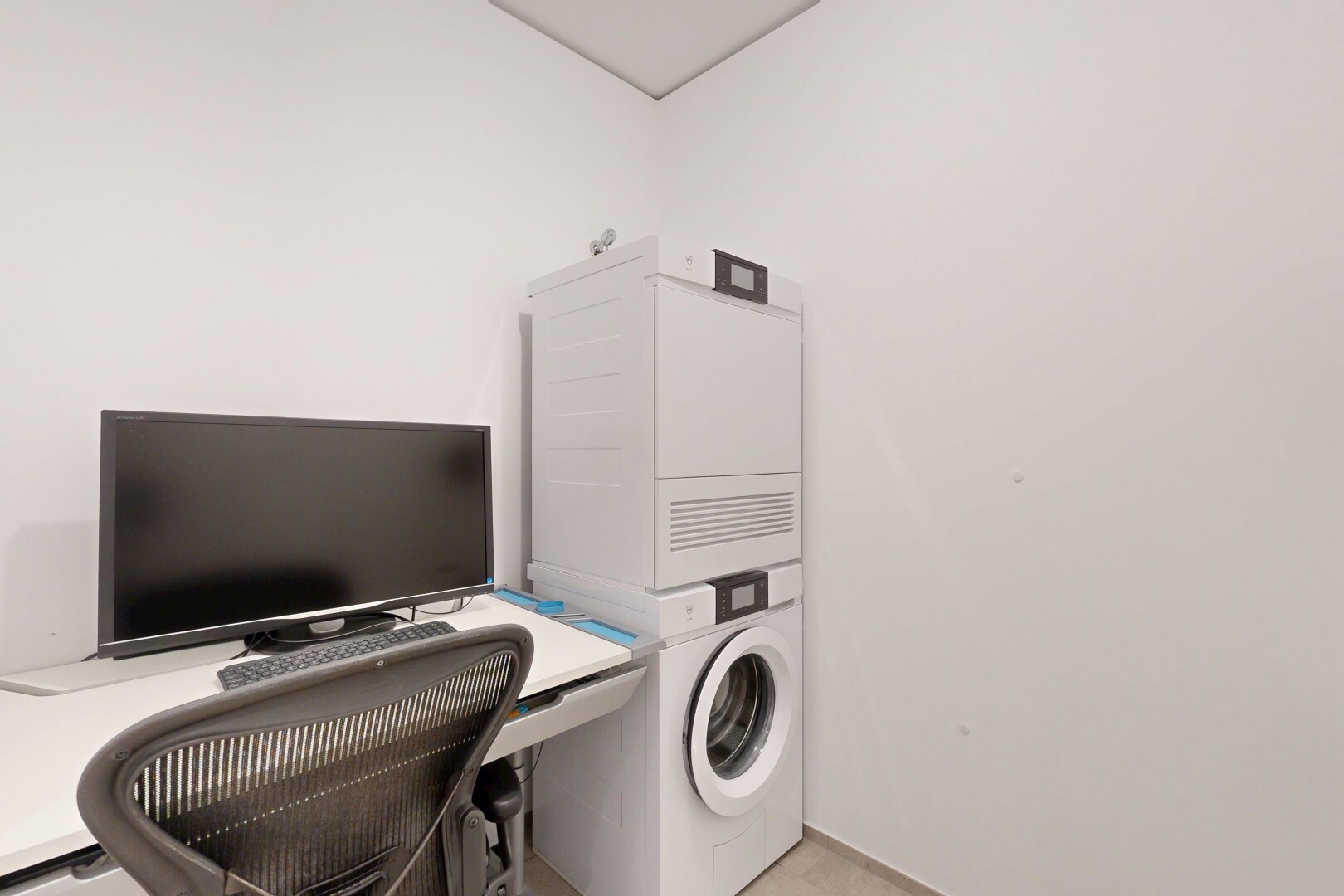 laundry area featuring a desk and stacked washer / dryer