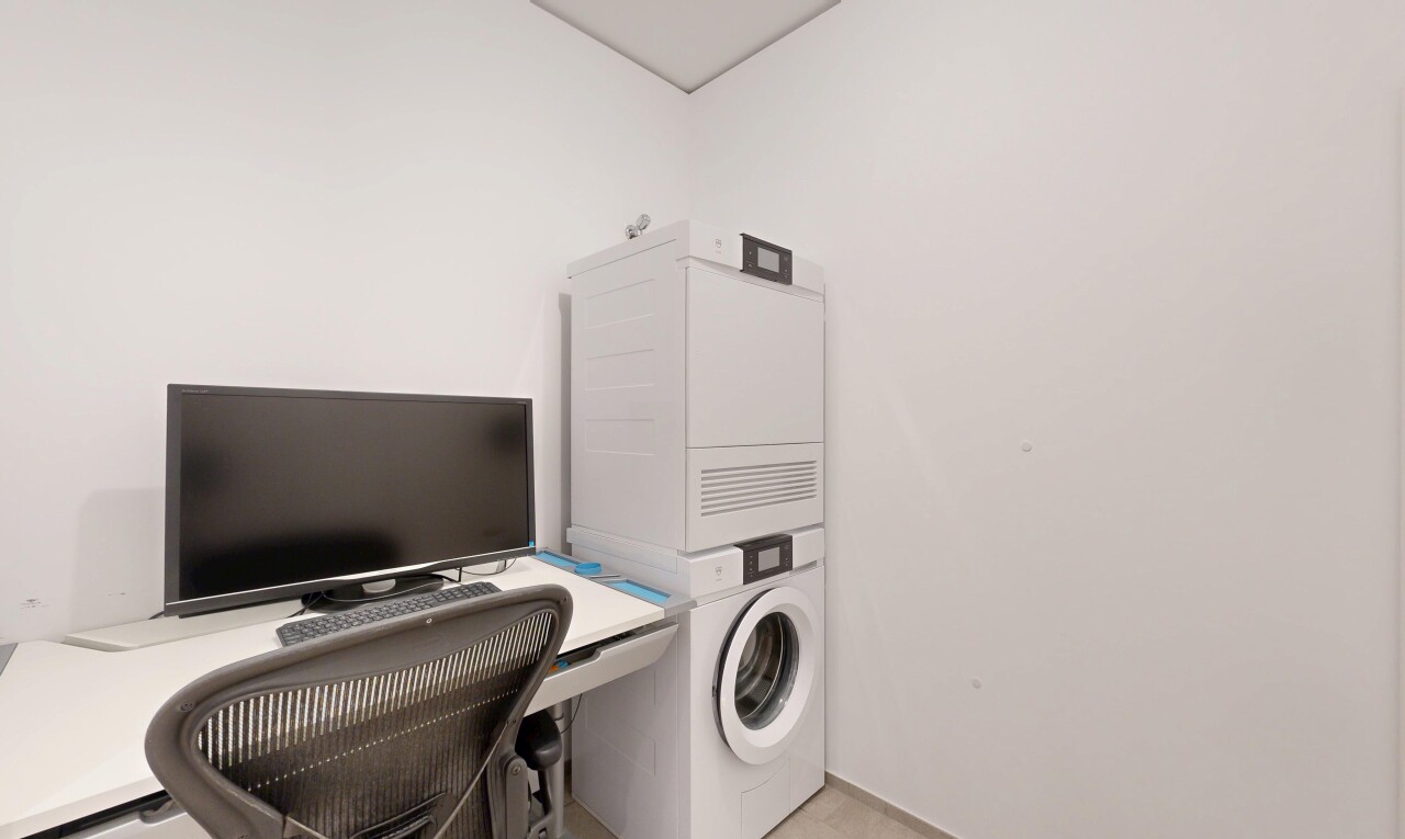 laundry area featuring a desk and stacked washer / dryer