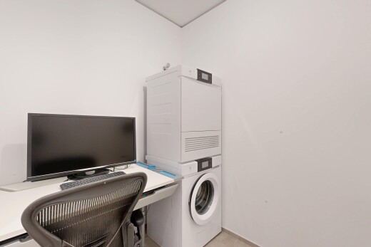 buanderie avec drywall, cloison sèche, espace bureau, télévision, et lave-linge et sèche-linge superposés