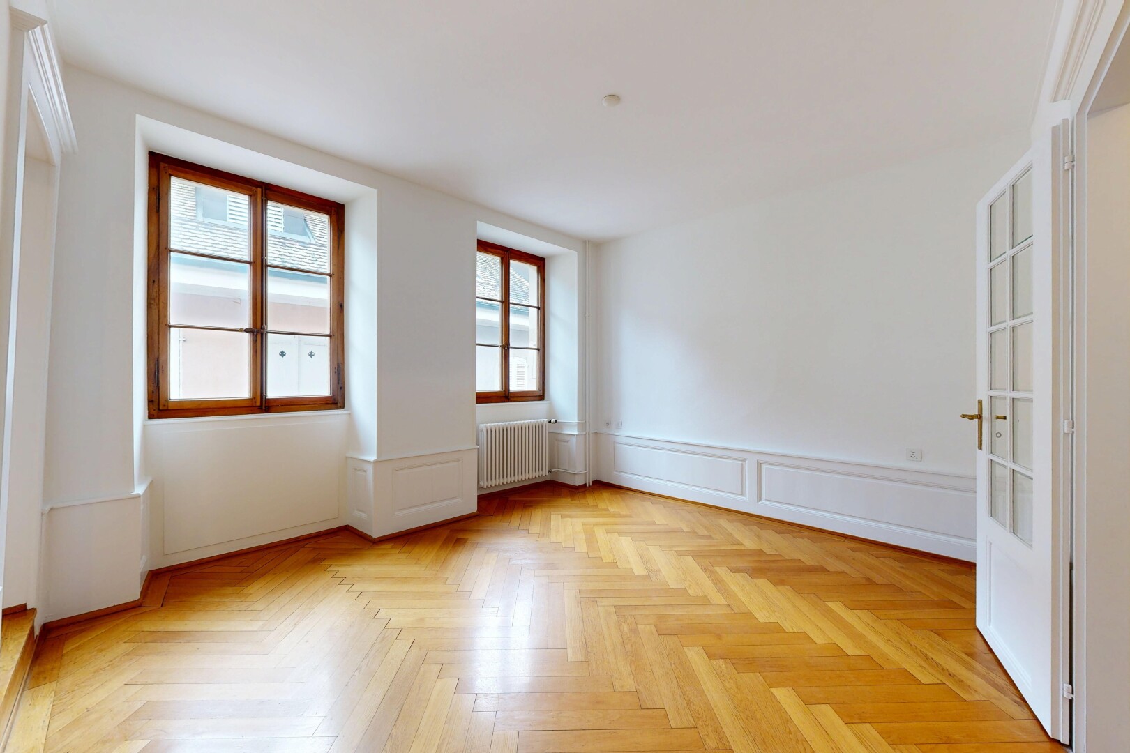 unfurnished room featuring parquet flooring, wainscoting, a decorative wall, and radiator heating unit