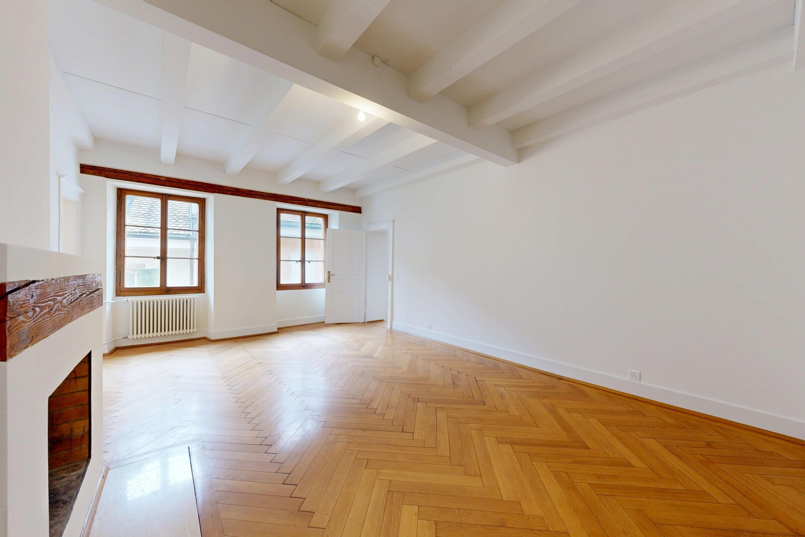 unfurnished room with parquet flooring, radiator, beam ceiling, and a fireplace