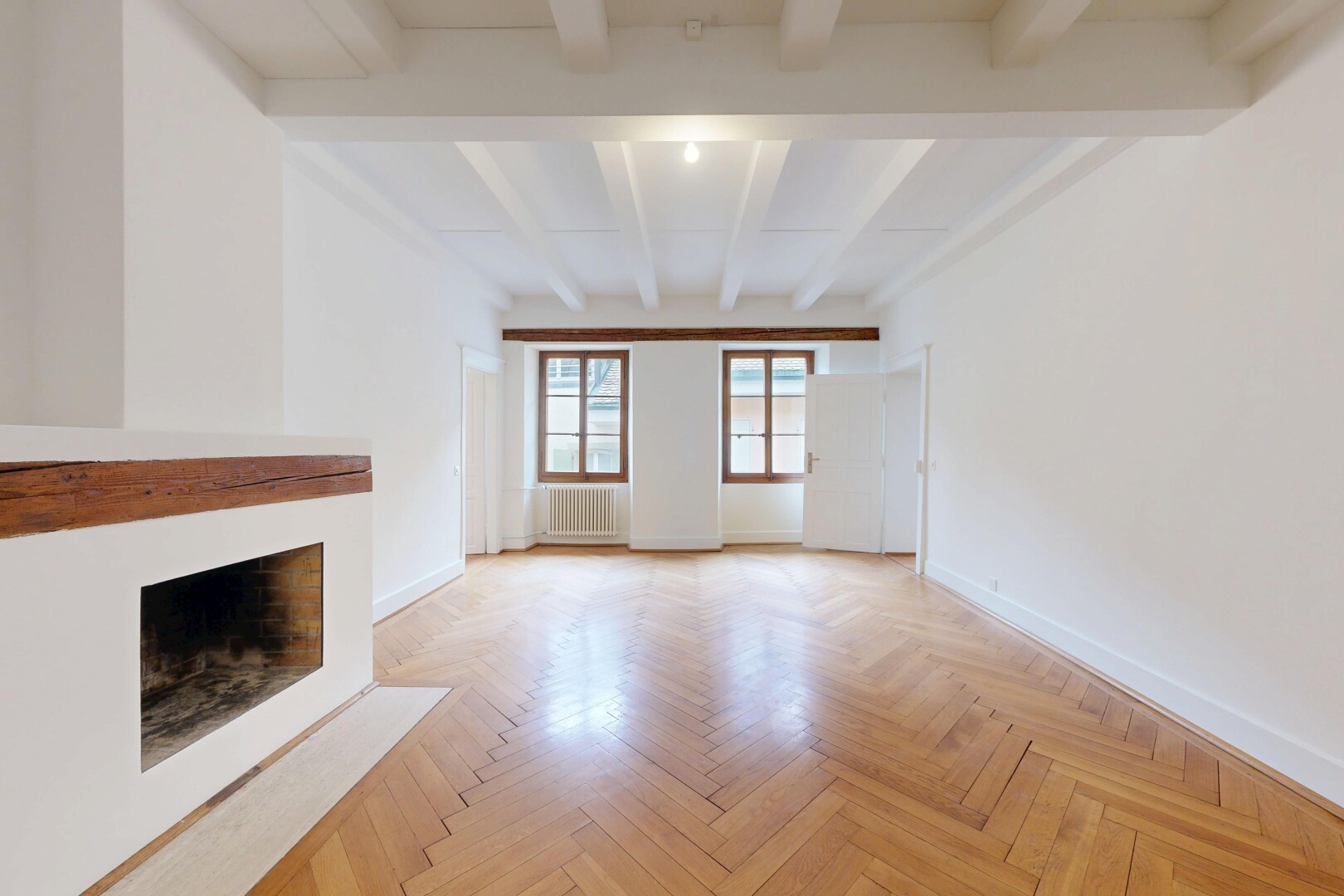 empty room with parquet floors, a fireplace with flush hearth, beamed ceiling, and radiator heating unit