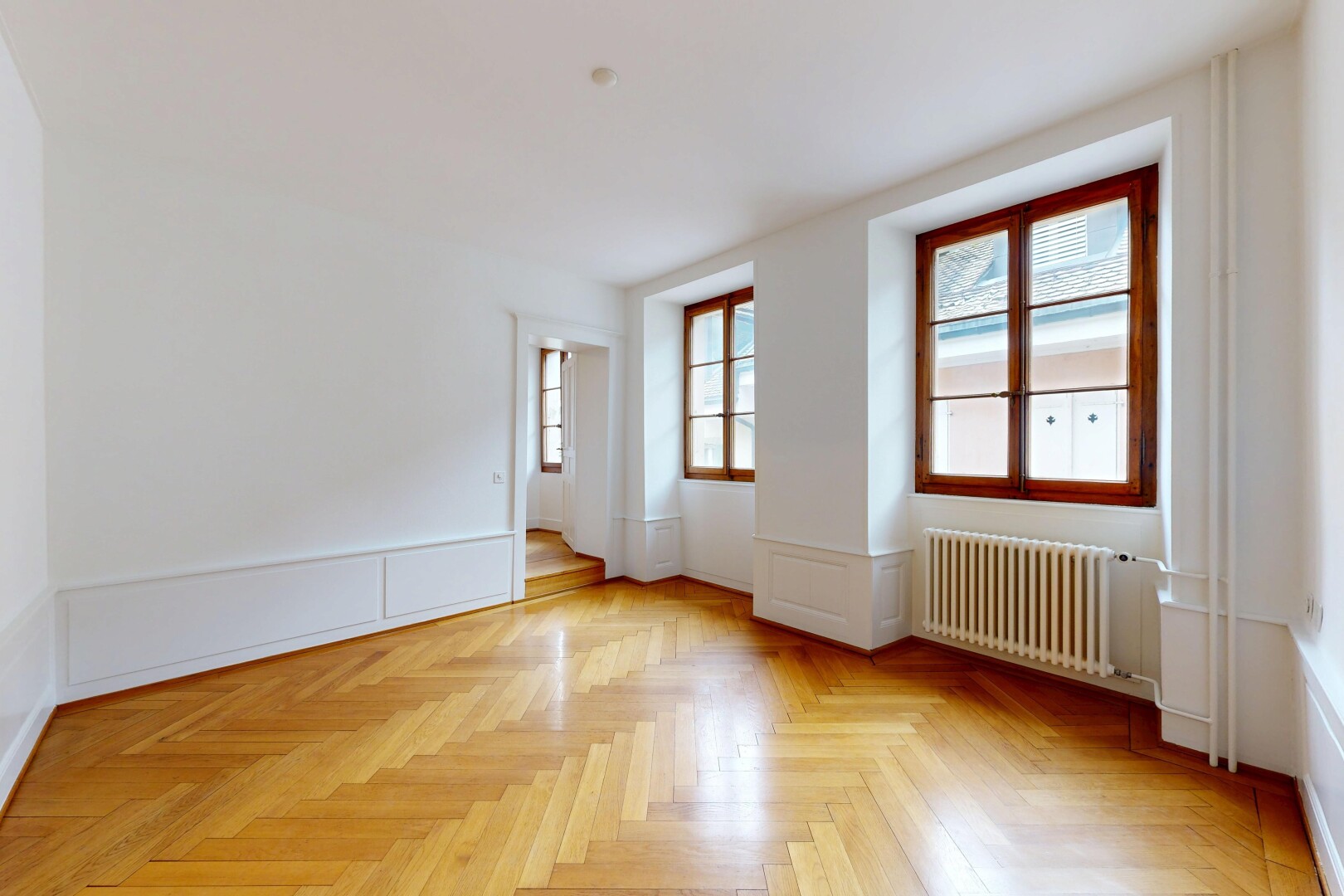 spare room with radiator heating unit, wainscoting, parquet floors, and a decorative wall