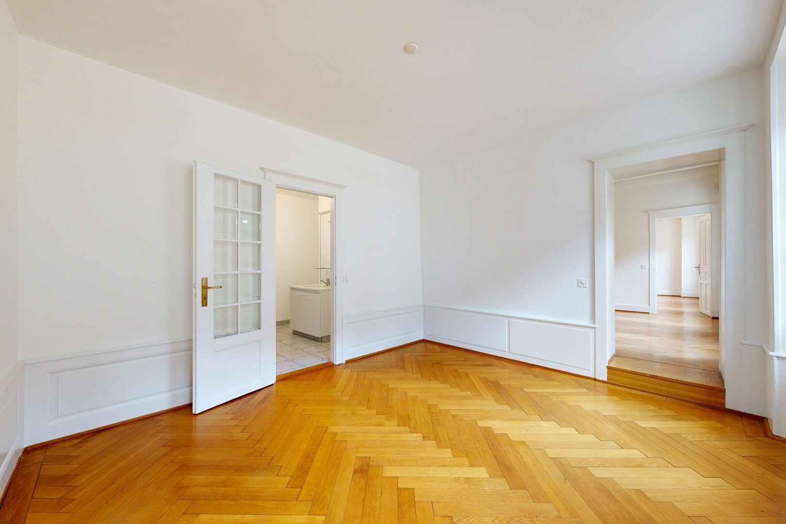 unfurnished room featuring wainscoting, a decorative wall, and parquet flooring