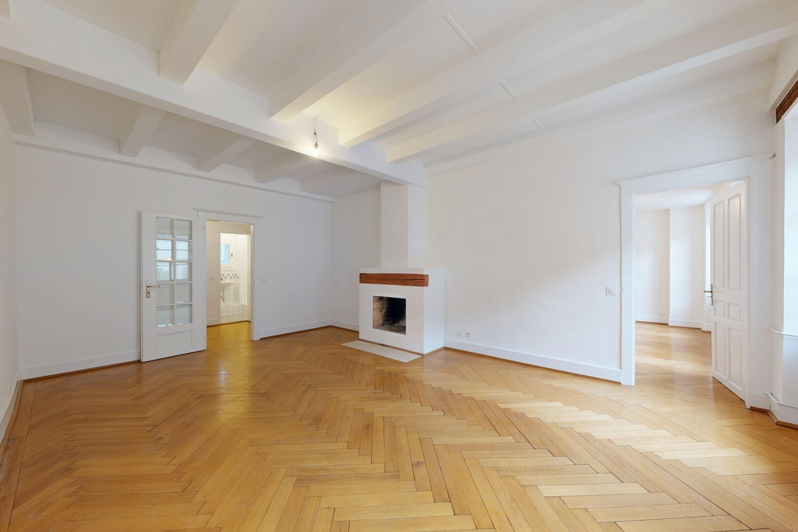 empty room with parquet floors, beamed ceiling, and a fireplace with flush hearth