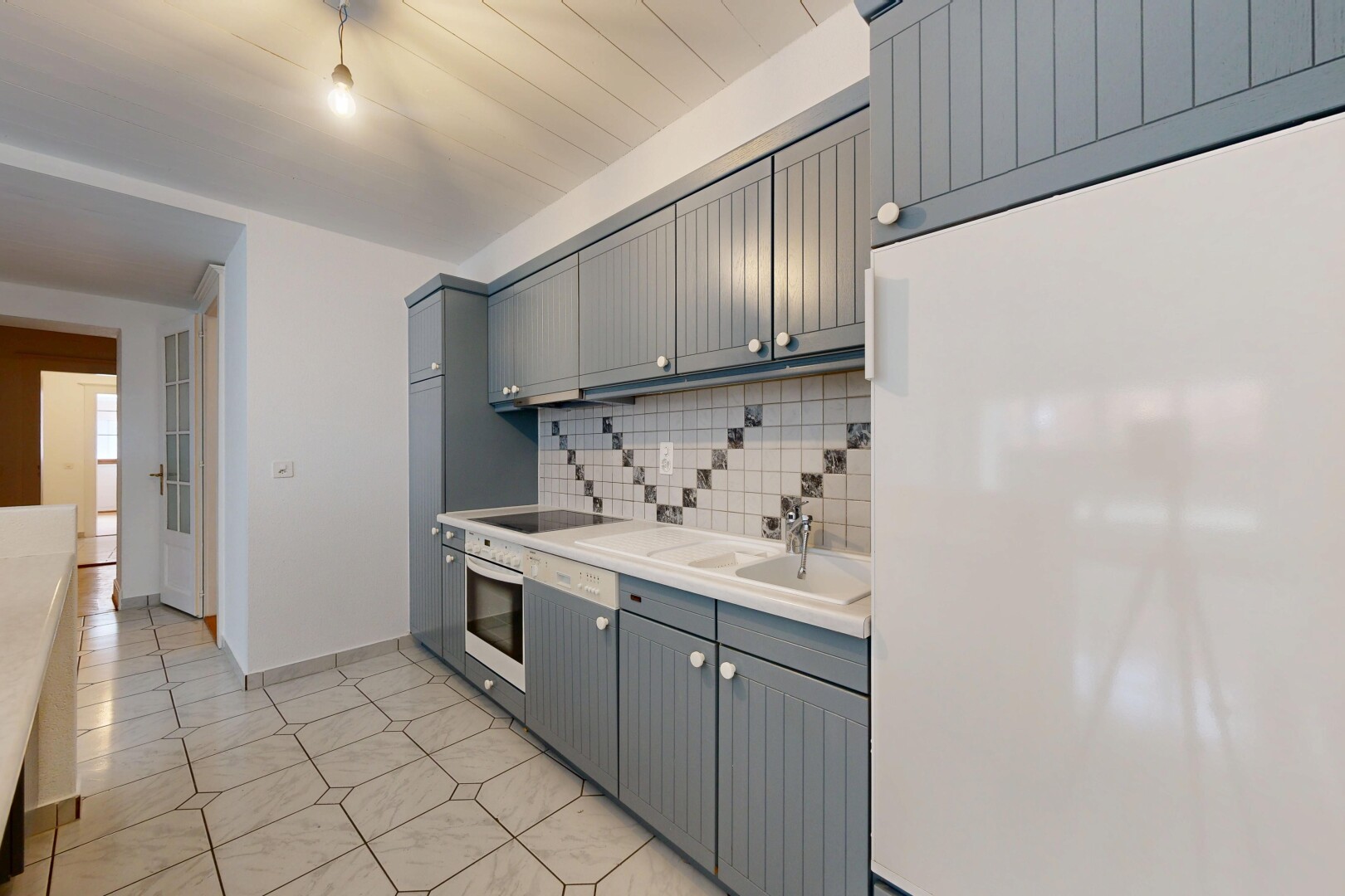 kitchen featuring freestanding refrigerator, light countertops, gray cabinetry, stainless steel oven, and backsplash