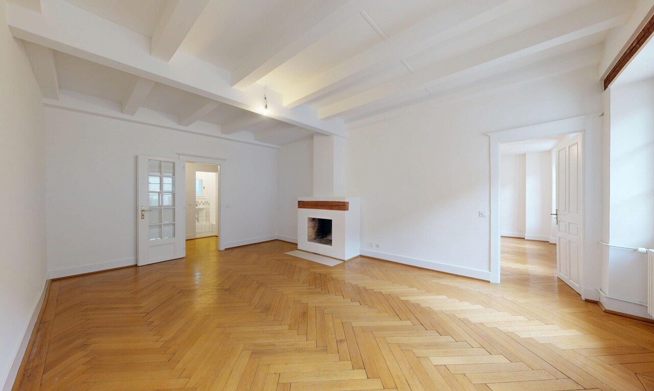empty room with parquet floors, beamed ceiling, and a fireplace with flush hearth