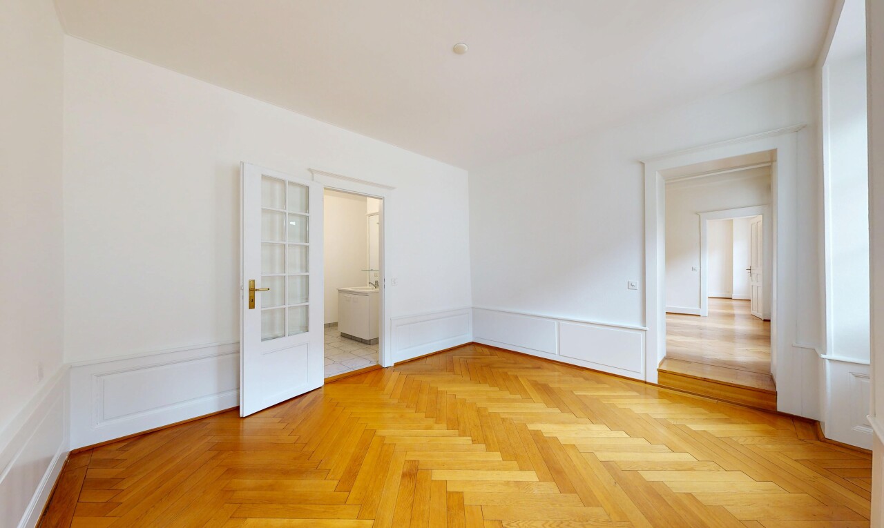 unfurnished room featuring wainscoting, a decorative wall, and parquet flooring