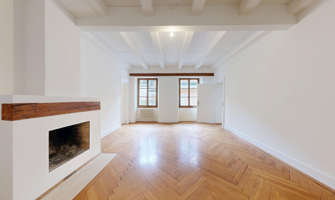 empty room with parquet floors, a fireplace with flush hearth, beamed ceiling, and radiator heating unit