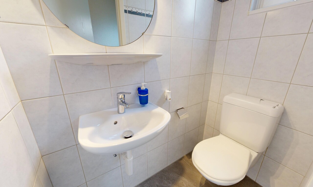salle de bains avec toilette, miroir, mur en carrelage, tile wall, et inside property