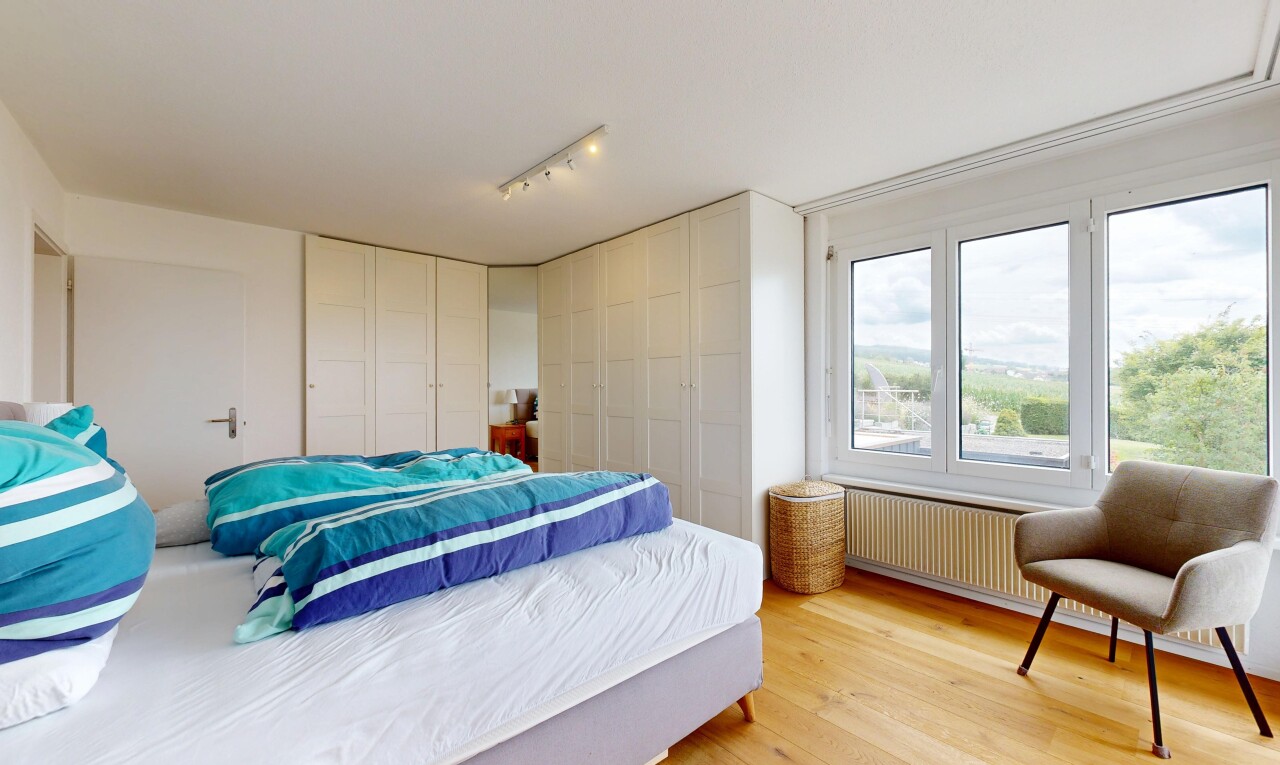 room with light wood-style flooring, rail lighting, radiator, and multiple closets
