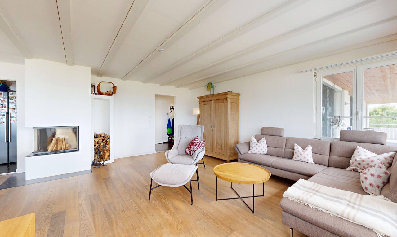 living area with beam ceiling, light wood finished floors, and a glass covered fireplace