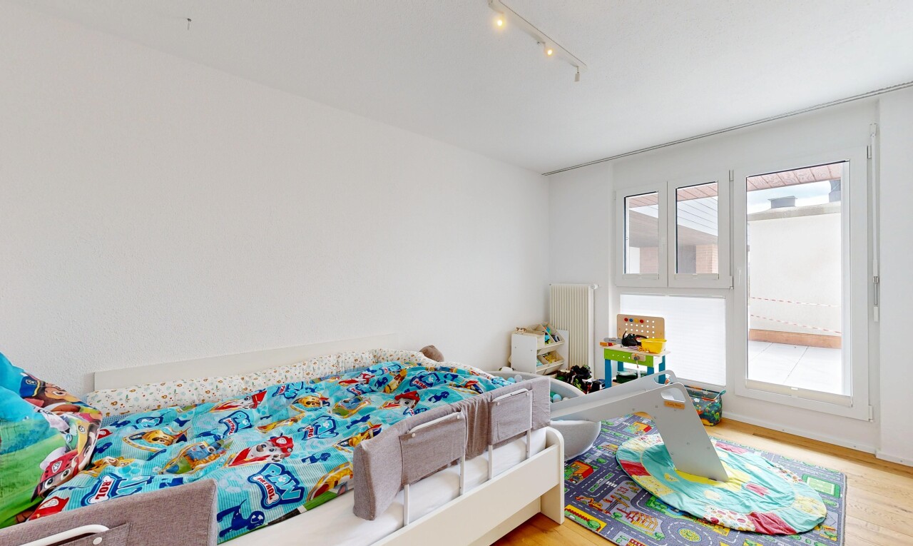 room featuring light wood-style floors, track lighting, and radiator heating unit