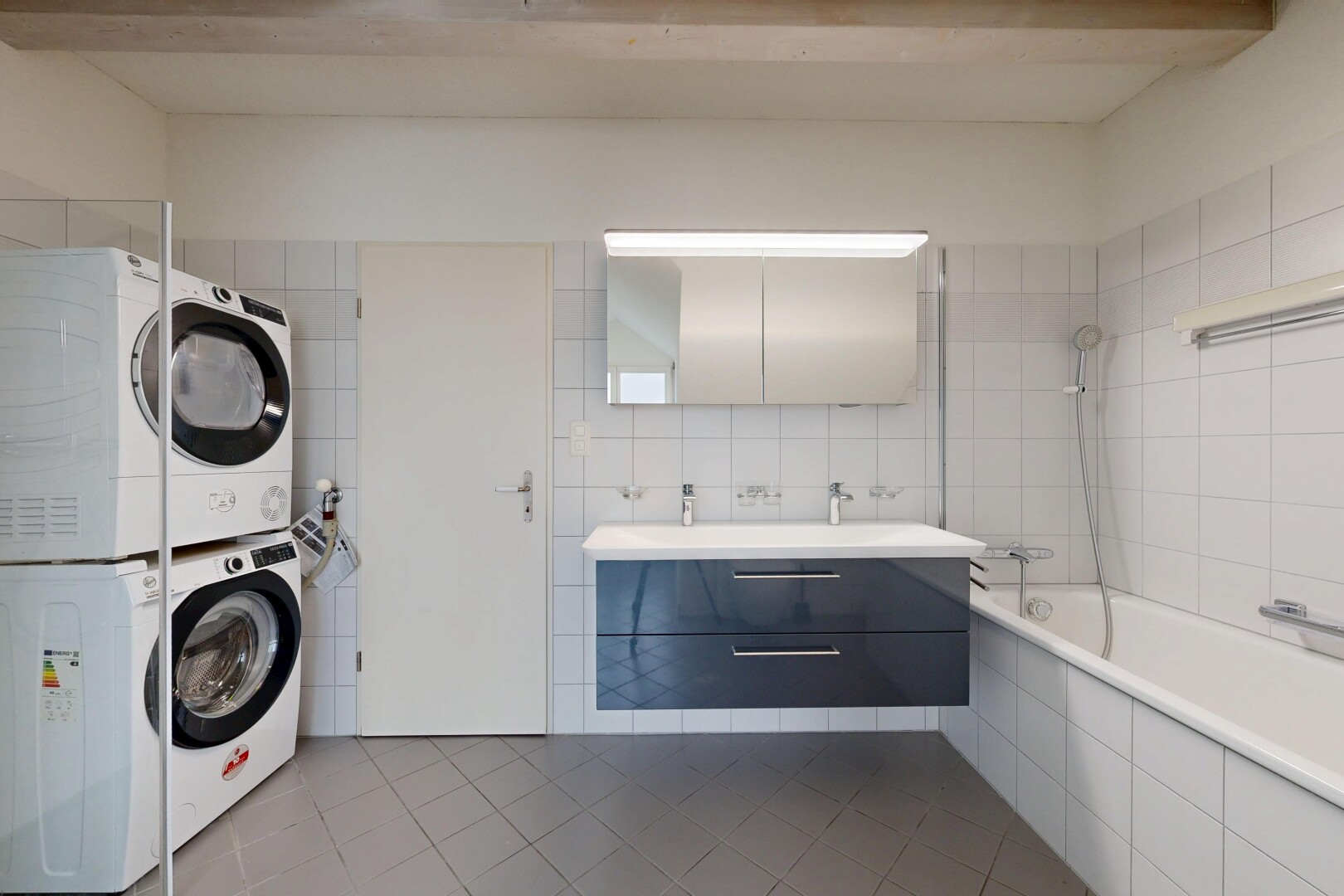 full bathroom featuring tile patterned floors, vanity, tile walls, stacked washing machine and dryer, and tiled shower / bath