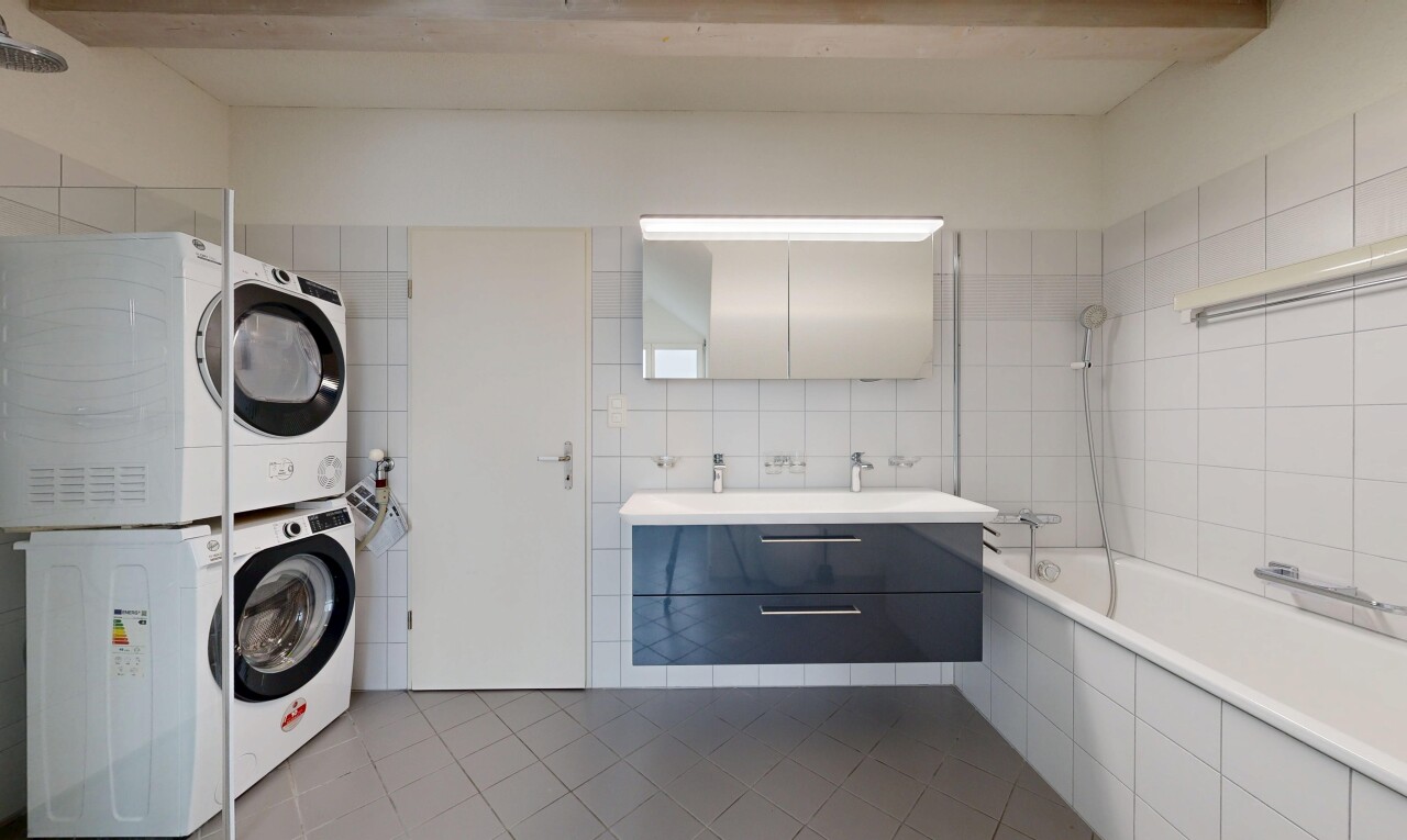 full bathroom featuring tile patterned floors, vanity, tile walls, stacked washing machine and dryer, and tiled shower / bath