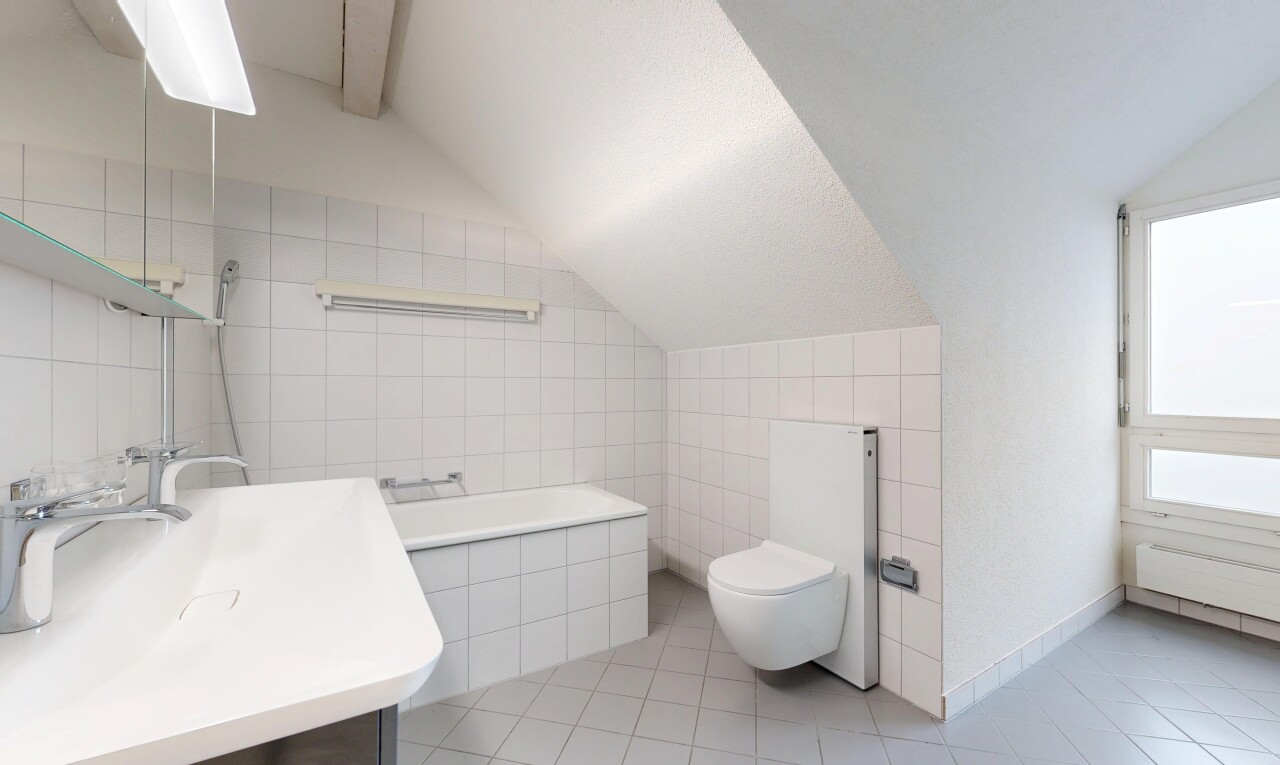 bathroom featuring tile walls, lofted ceiling, vanity, light tile patterned floors, and tiled tub