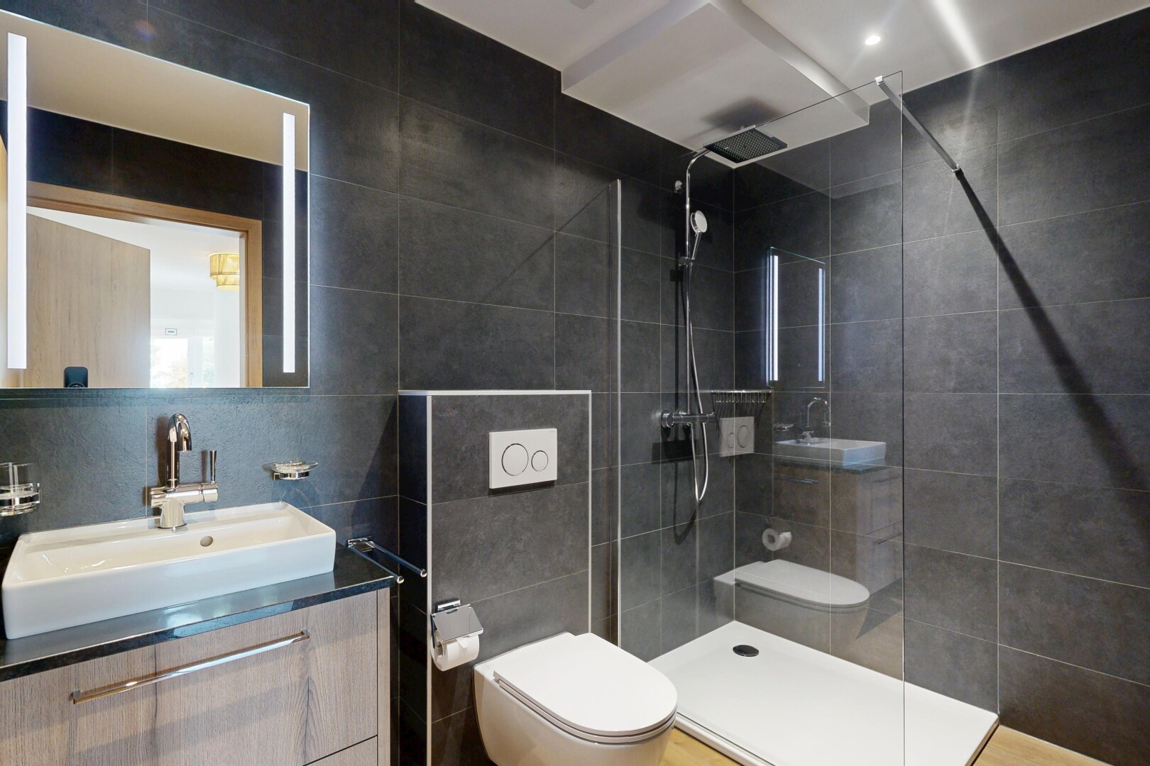salle de bains avec mur en carrelage, tile wall, miroir, lavabo (ou coiffeuse selon le contexte), et toilette