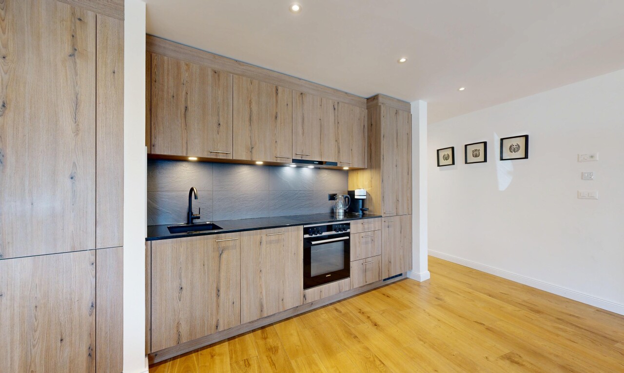 cuisine avec four, cloison sèche, drywall, inside property, et sol en finition bois