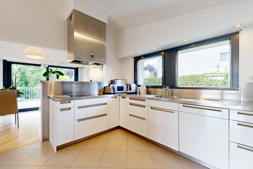 cuisine avec plans de travail en acier inoxydable, évier, armoires blanches, inside property, et armoires à panneau plat