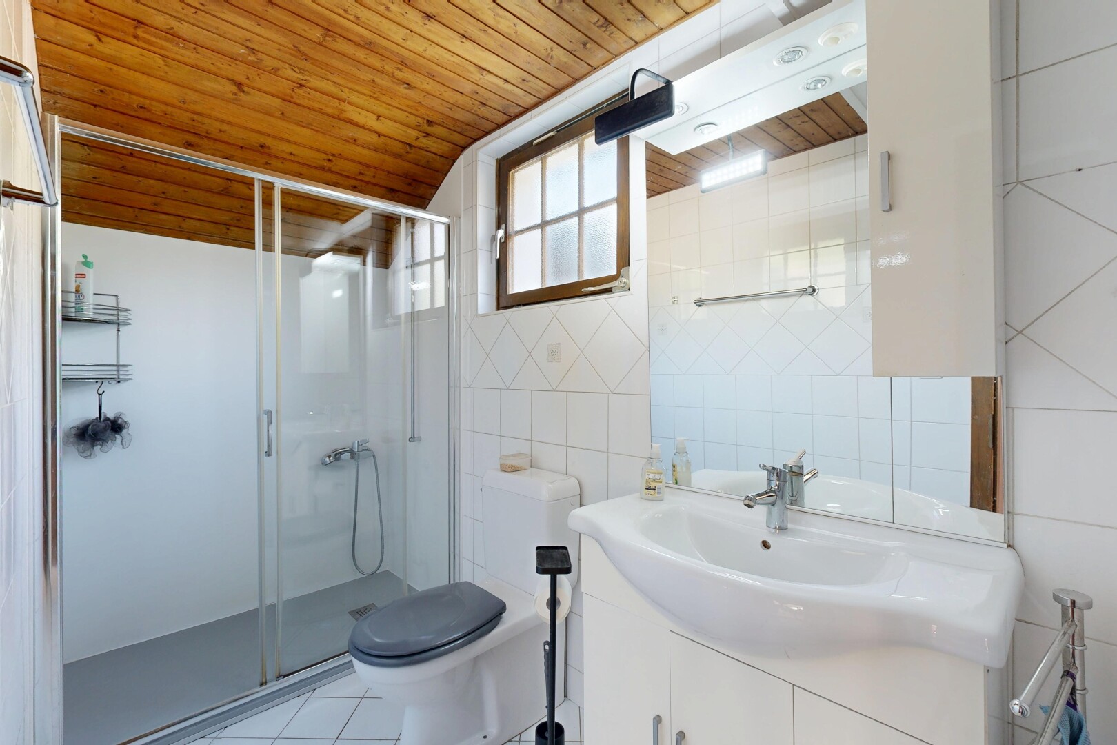 salle de bains avec lavabo (ou coiffeuse selon le contexte), plafond en bois, wood ceiling, miroir, et douche