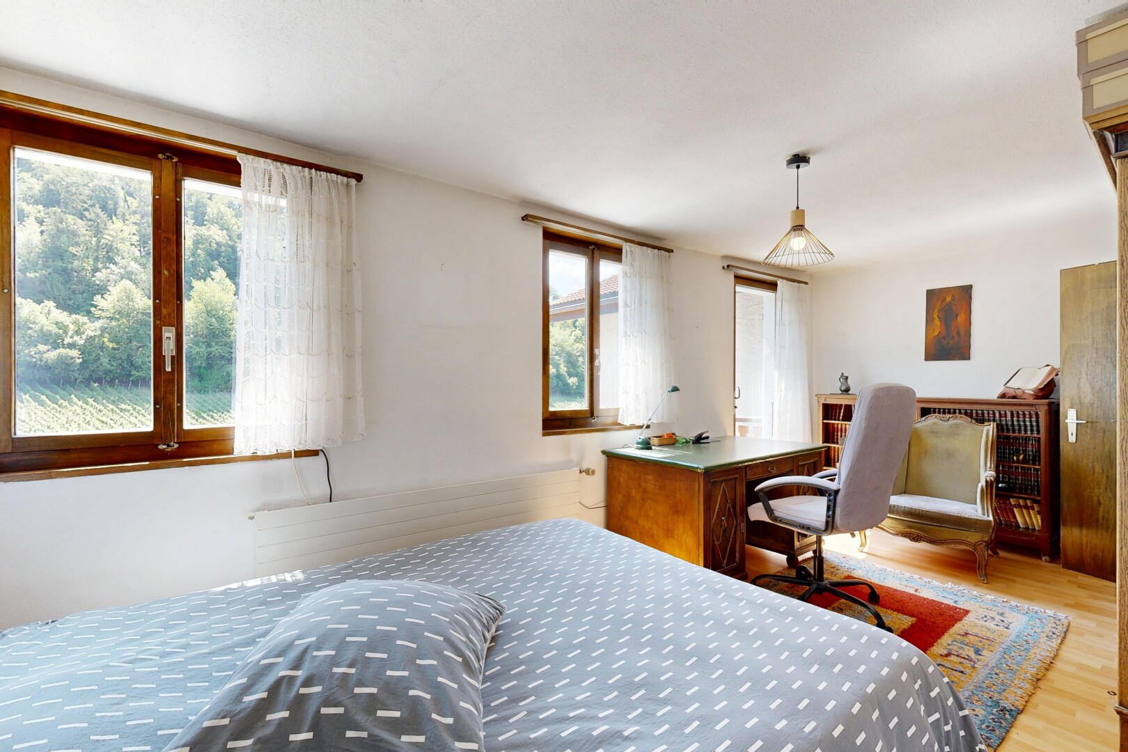 chambre avec espace bureau, cloison sèche, drywall, éclairage suspendu, et sol en finition bois