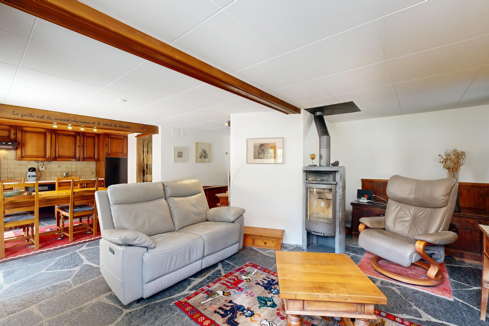 salon / salle à manger avec éclairage sur rail, drywall, cloison sèche, poêle à bois, et inside property