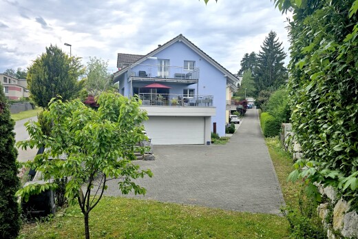 façade avec garage intégré, bardage en stuc, allée, property visible, et balcon