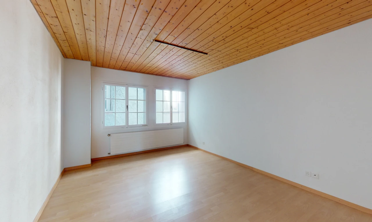 chambre vide avec parquet, lumière naturelle, et radiateur