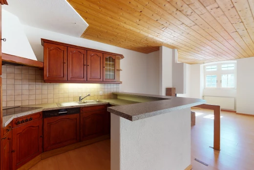 cuisine avec plafond voûté, parquet, lumière naturelle, hotte, cuisinière électrique, armoires marrons, comptoirs claires, et sol clair