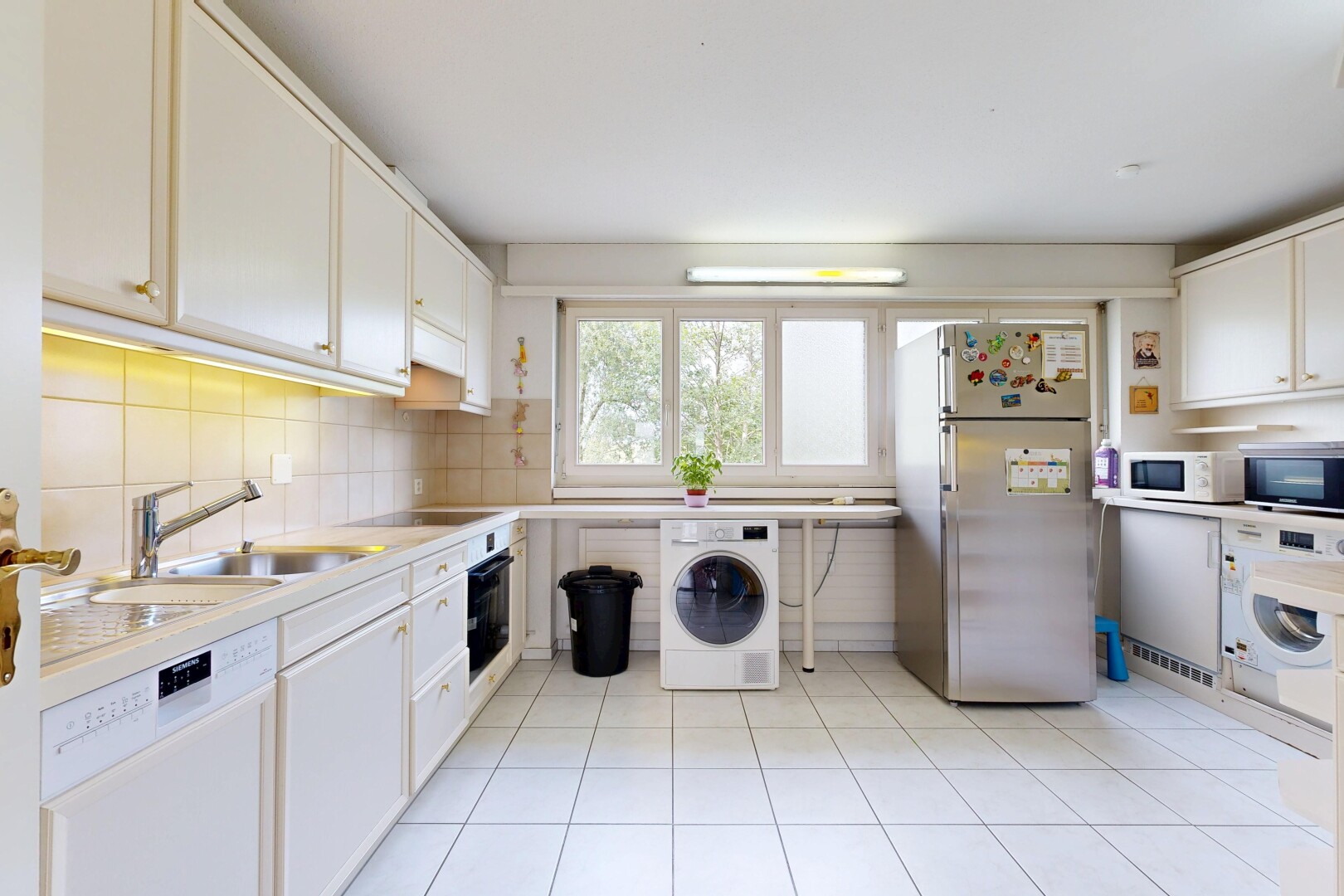kitchen with stainless steel appliances, washer / dryer, white cabinets, backsplash, and light tile patterned floors