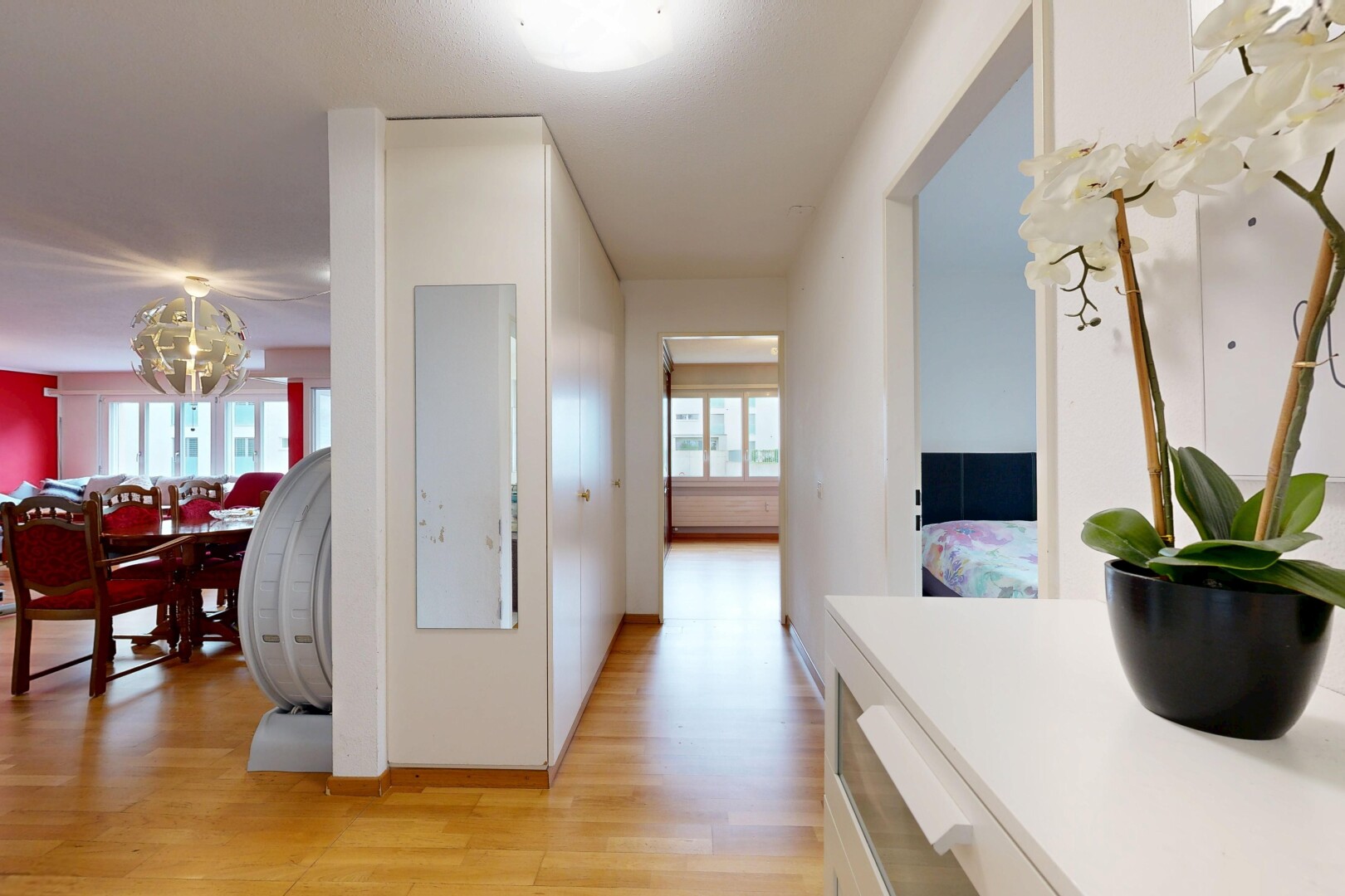 corridor with light wood-style floors, healthy amount of natural light, and hanging lights