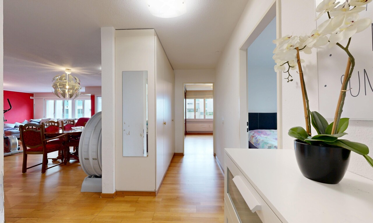 corridor with light wood-style floors, healthy amount of natural light, and hanging lights