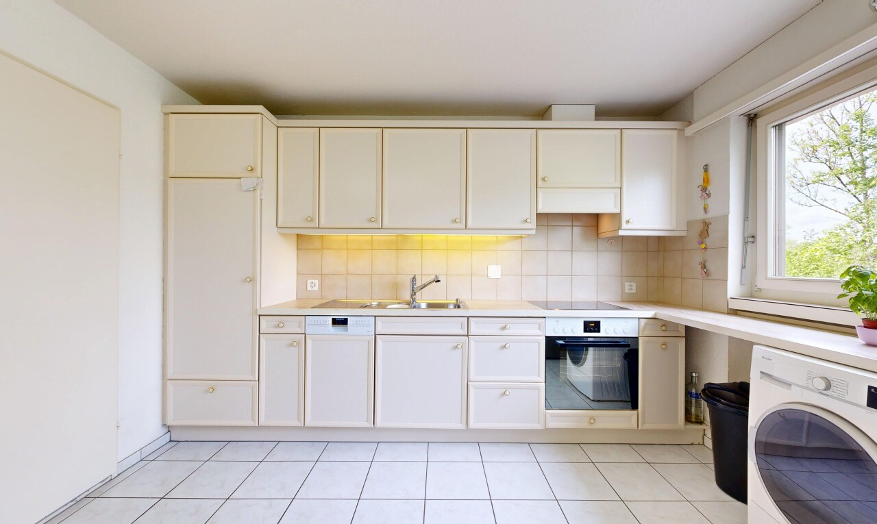 kitchen featuring wall oven, washer / dryer, light countertops, and backsplash