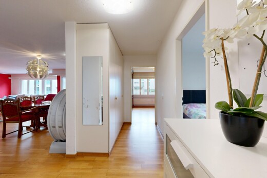 corridor with light wood-style floors, healthy amount of natural light, and hanging lights