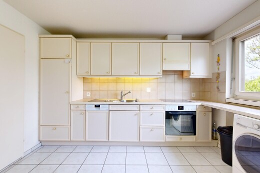 kitchen featuring wall oven, washer / dryer, light countertops, and backsplash