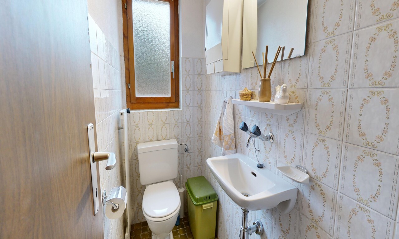 half bath featuring toilet and tile walls