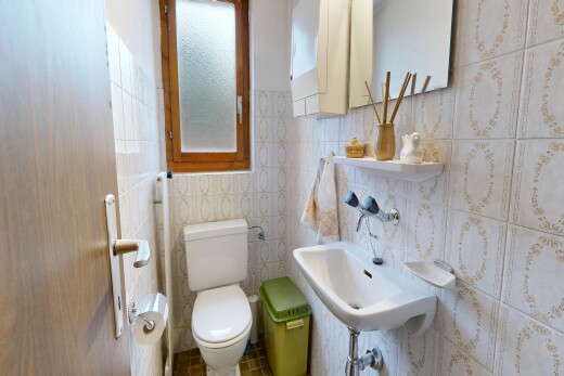 half bath featuring toilet and tile walls