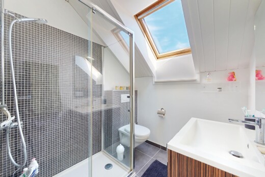 salle de bains avec puits de lumière, lavabo (ou coiffeuse selon le contexte), douche, toilette, et sol en carrelage