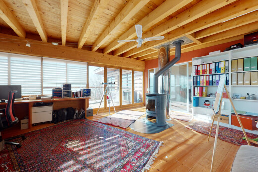 bureau avec télévision, sol en finition bois, wood finish floor, poêle à bois, et plafond à poutres