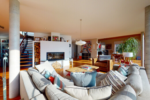 living area featuring ornate columns, a glass covered fireplace, wood finished floors, and stairway