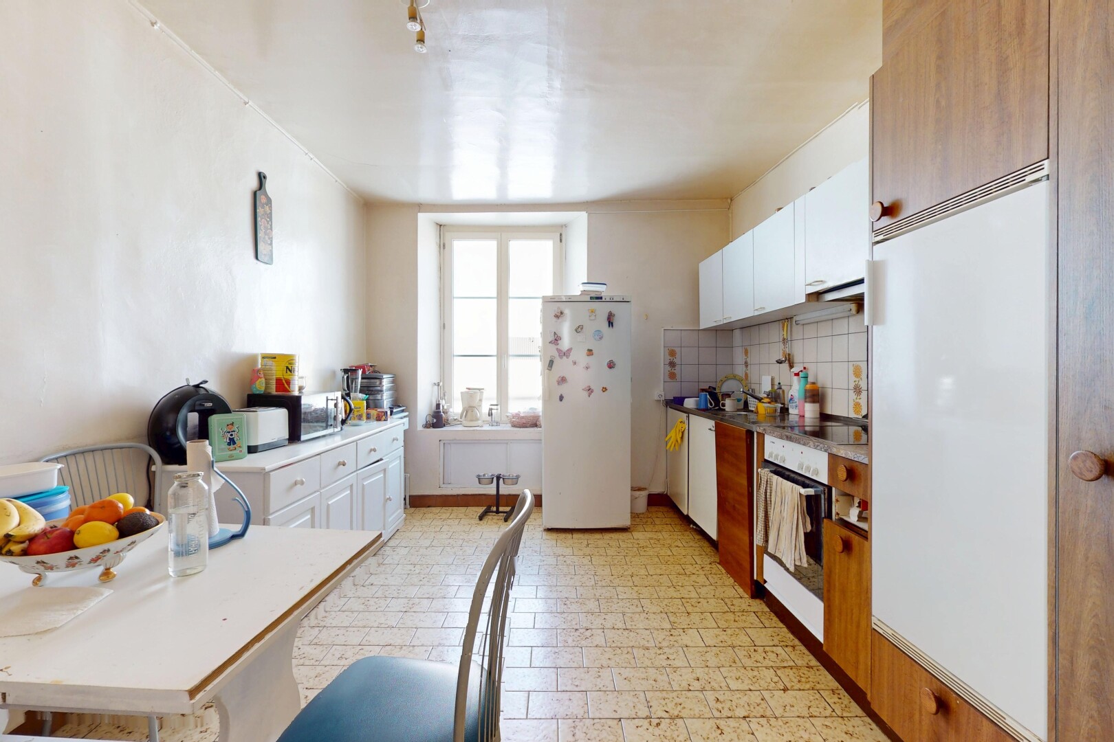 cuisine avec armoires blanches, réfrigérateur, plans de travail, et four