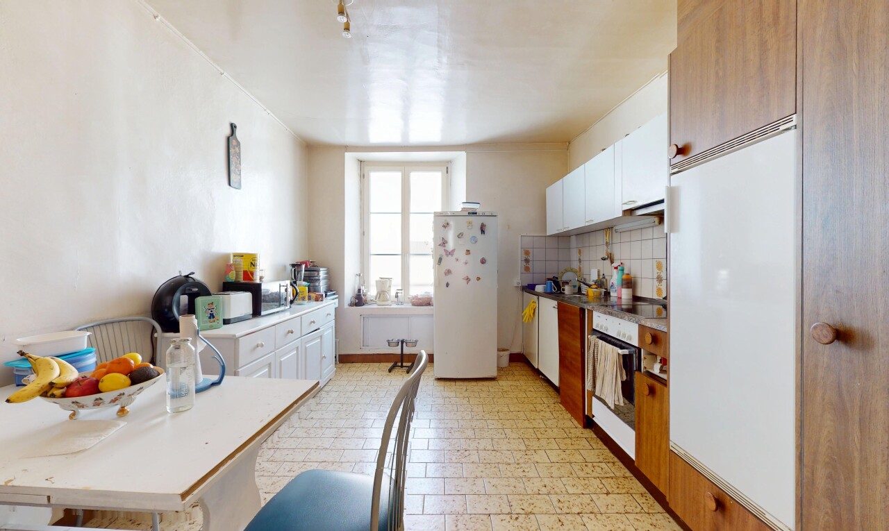 cuisine avec armoires blanches, réfrigérateur, plans de travail, et four