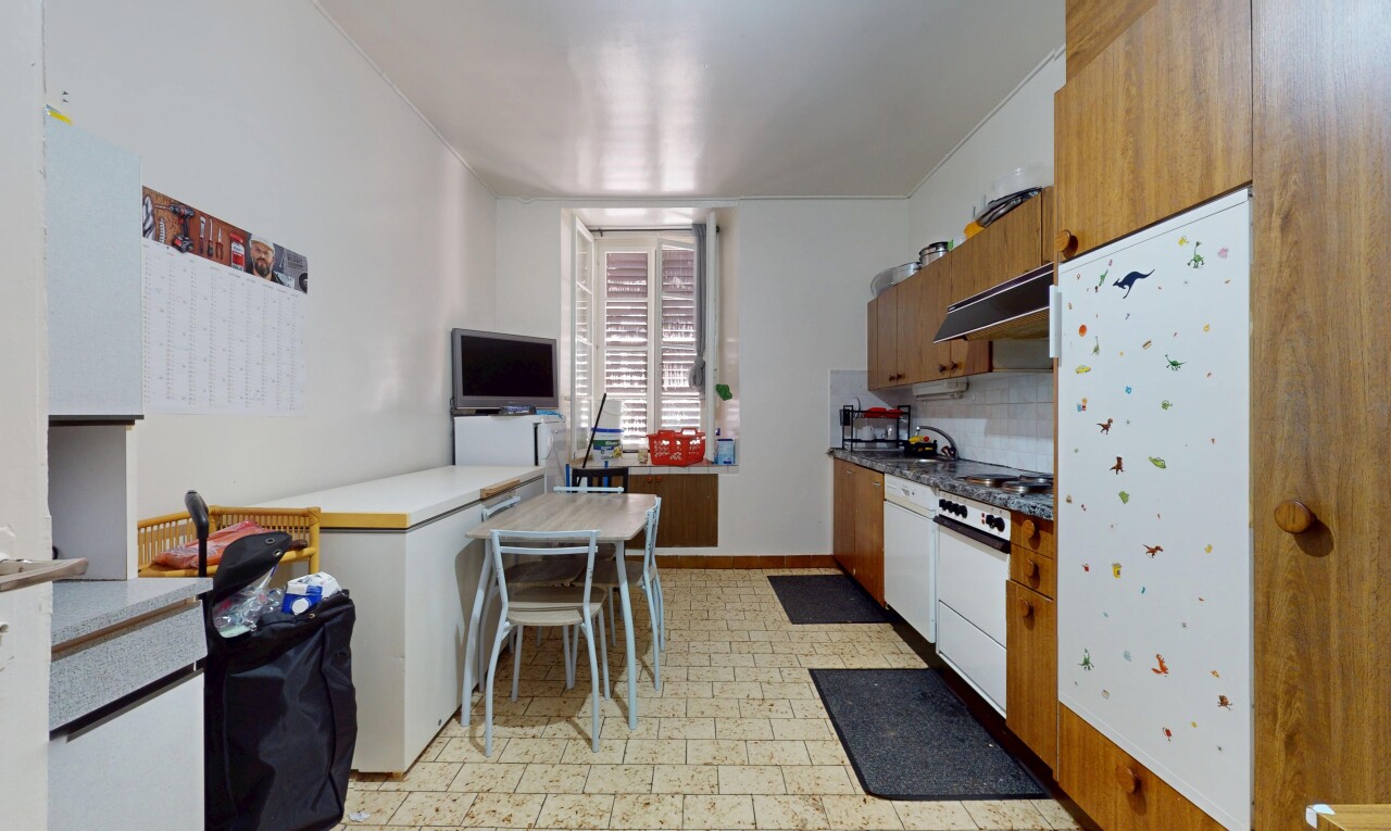 cuisine avec armoires marron moyen, sol en vinyle, télévision, hotte, et cloison sèche