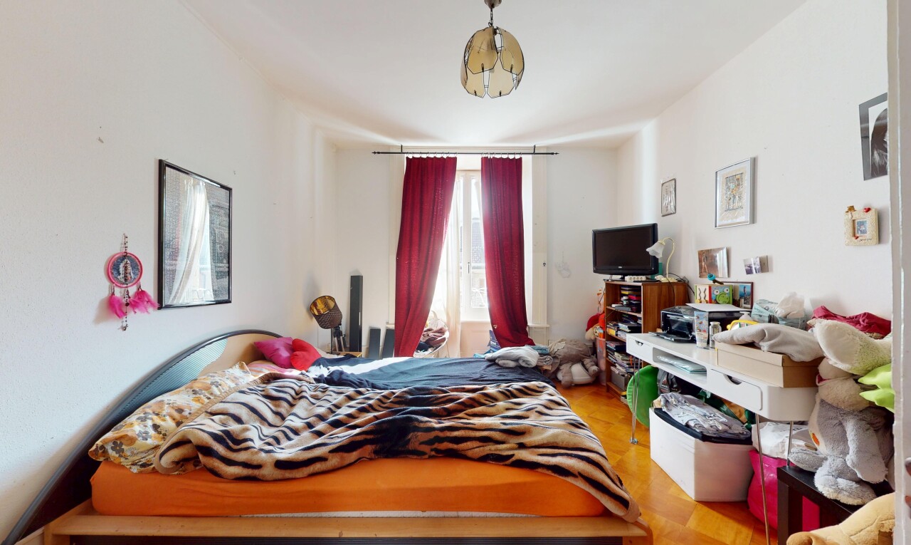 chambre avec lumière naturelle, cloison sèche, sol en finition bois, et télévision