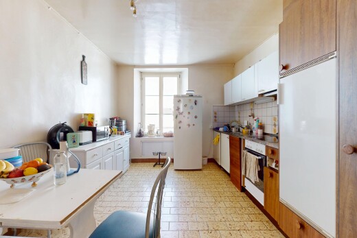 cuisine avec armoires blanches, réfrigérateur, plans de travail, et four